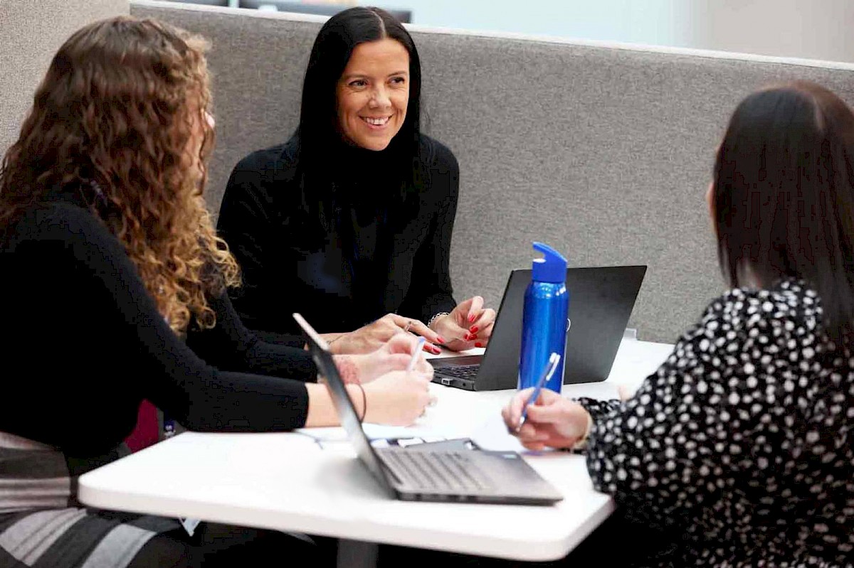 A group of female colleagues sat at a table enjoying a descussion