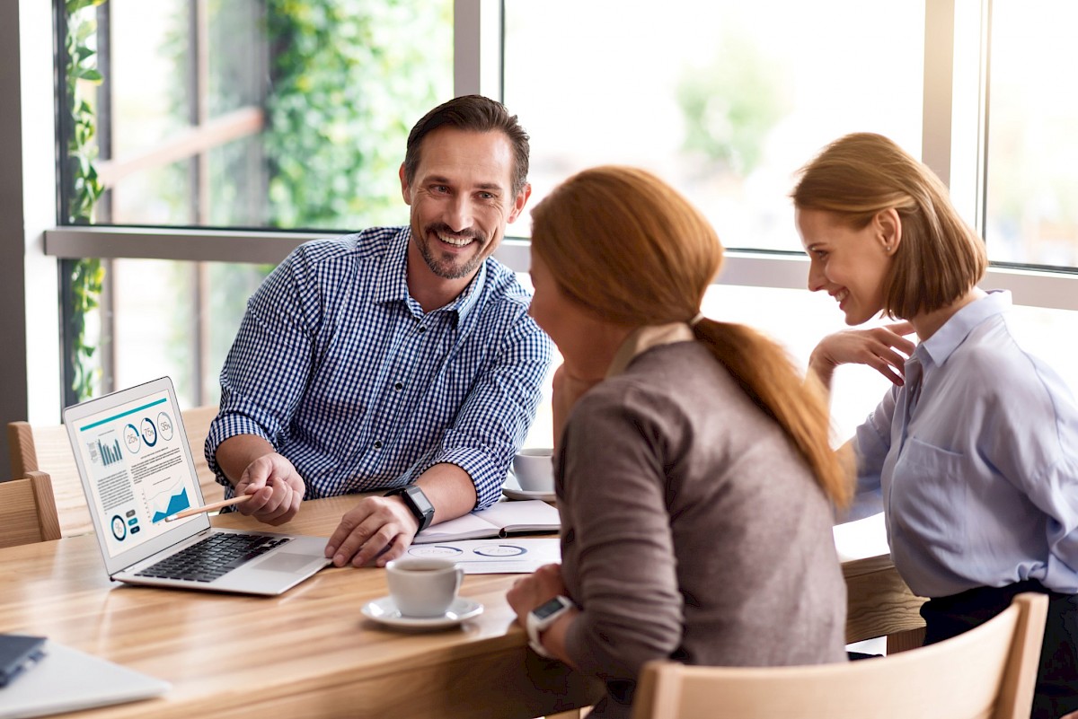 Young executive in meeting smiling and viewing laptop screen