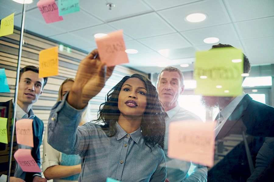 Project team viewing post it notes on a project board