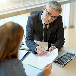 Male executive wearing glasses sharing information on a spreadsheet with a colleague