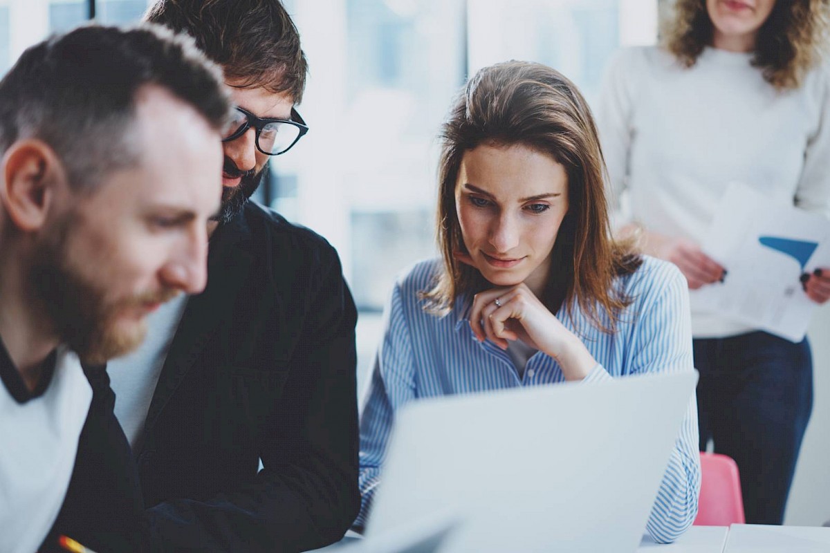 Professional team in meeting around laptop