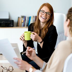 Young female colleagues talking and laughing enjoying a coffee