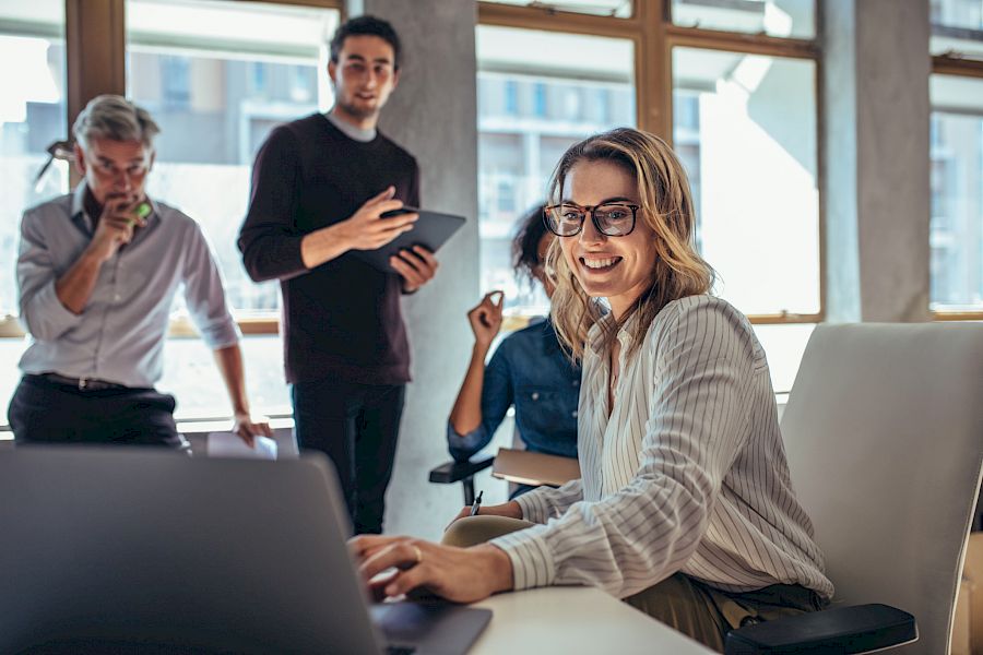 Team of colleagues viewing a laptop in office