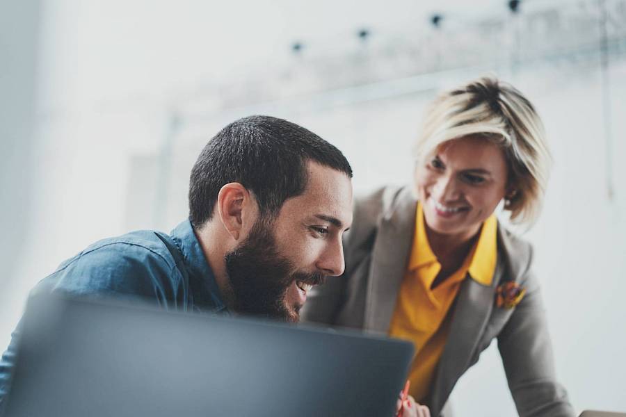 Male and female professional staring at a laptop and smiling