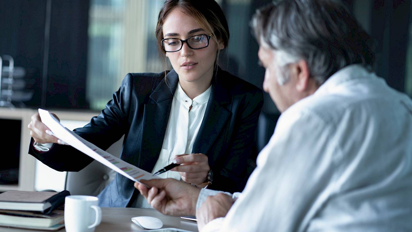 Executive women in glasses showing male client information on a document