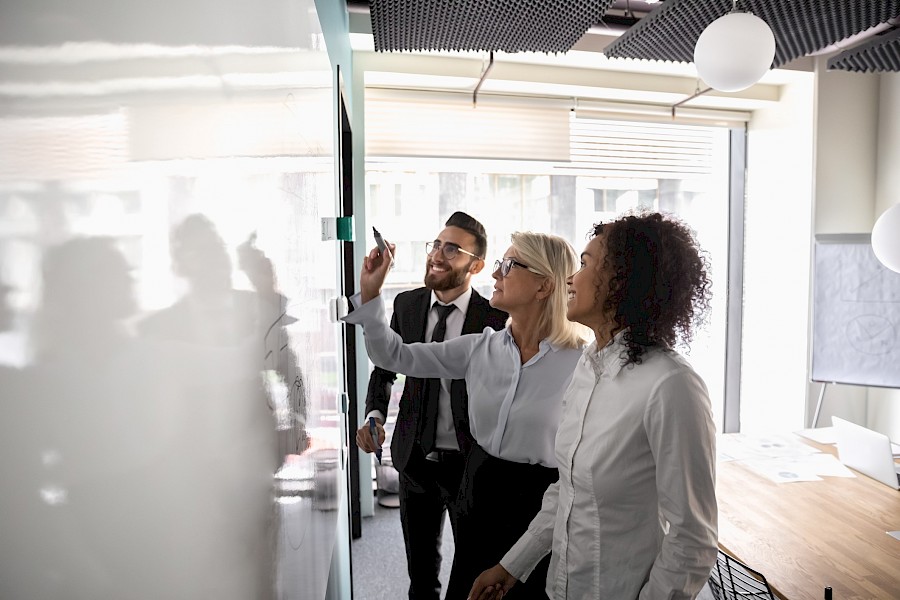 Colleagues huddled around a whiteboard