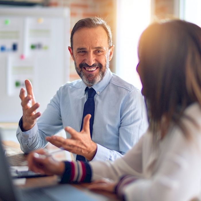 Executive male smiling and talking animatedly to a female executive