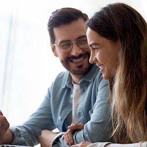 Young couple smiling and looking as a laptop screen