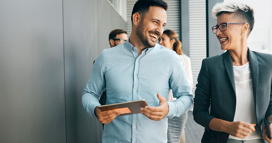 Male and female colleague walking and smiling