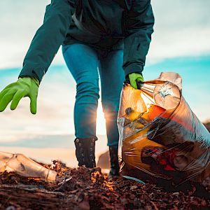 Person picking up rubbish on a beach at sunset