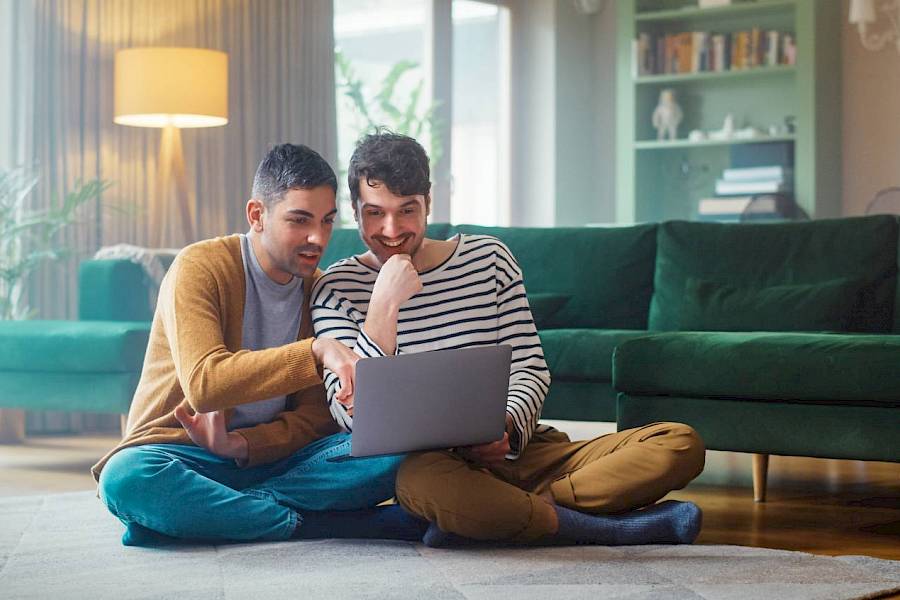 Male and female professional staring at a laptop and smiling