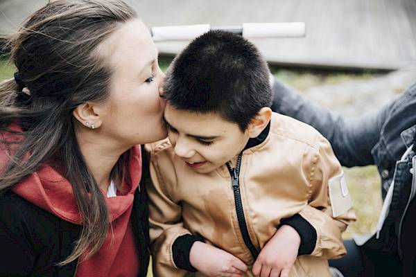 Women kissing her disabled son on the forehead