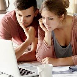 Young male and female couple in home looking at a laptop screen in concentration