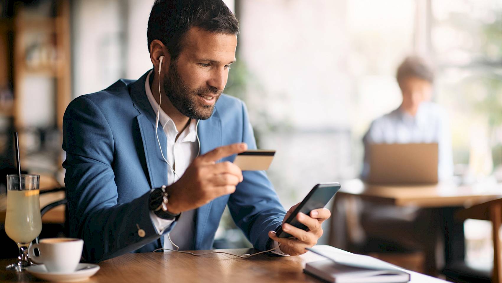 Professional young male in cafe making card payment on mobile phone