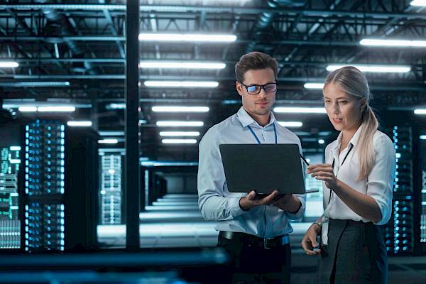 professional male and female laptop in computer server room