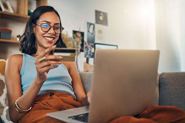 Smiling female making payment on laptop with bank card