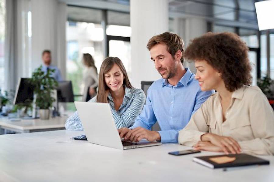 Team of colleagues viewing a laptop in office