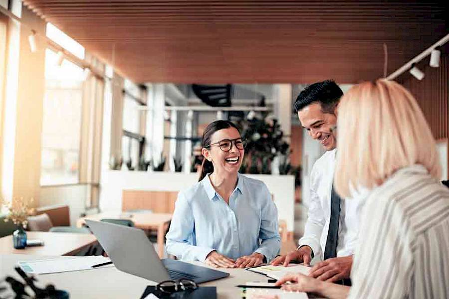 Informal team meeting, male and female colleagues standing and smiling