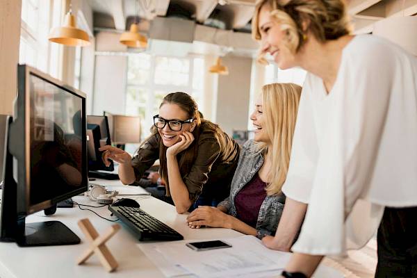 professional  female team smiling reading shared copmuter screen