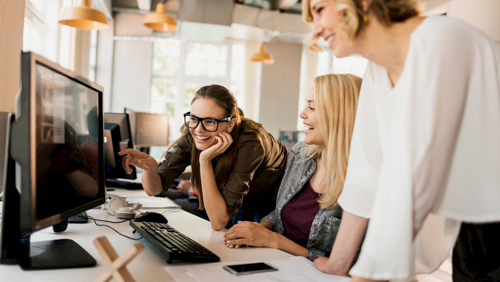 professional female team smiling reading shared computer screen