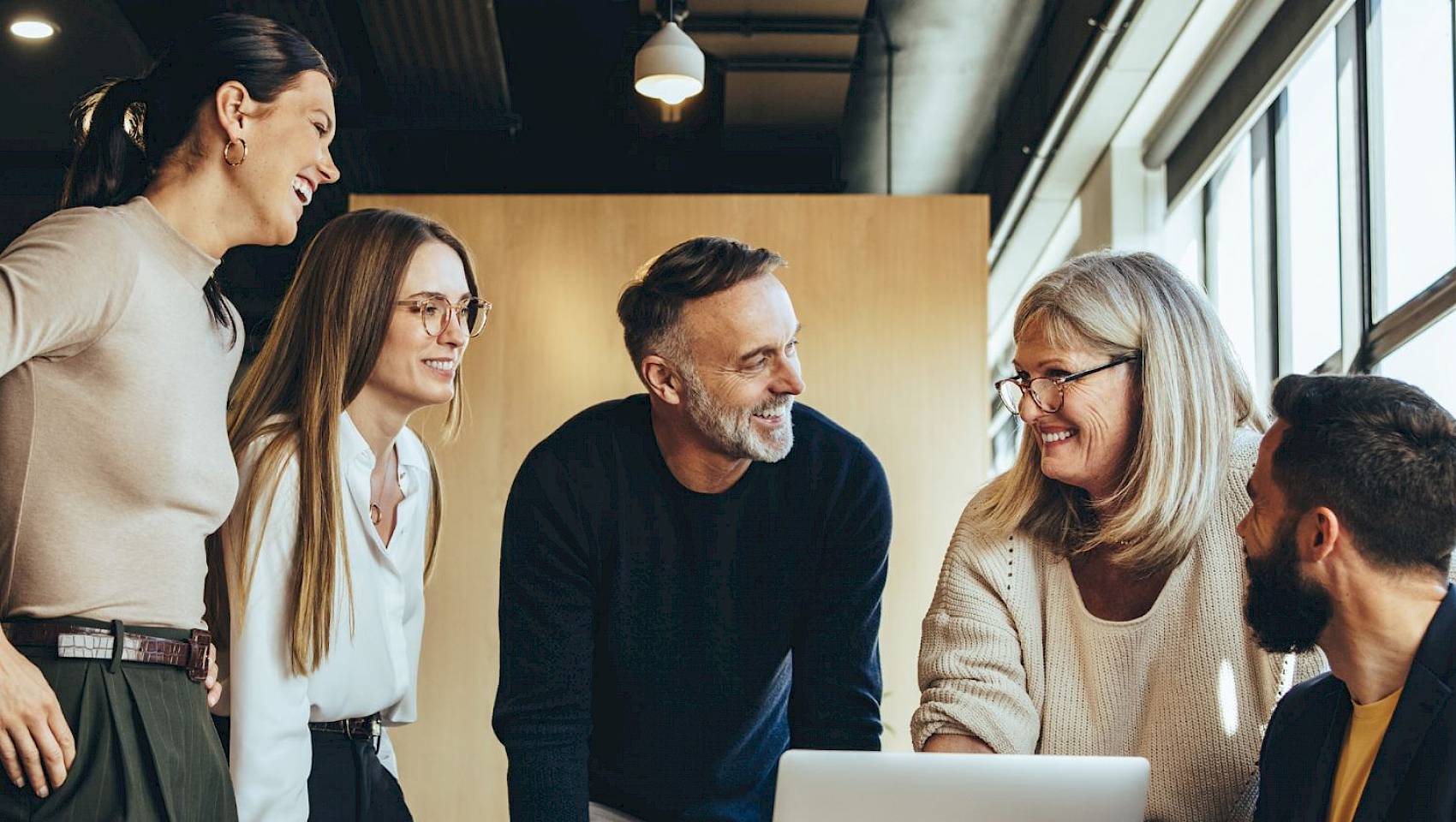 professional male and female team looking at laptop screen smiling in office setting