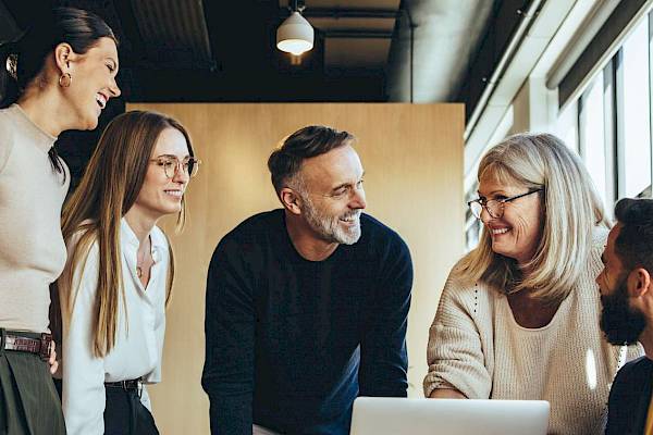 professional male and female team looking at laptop screen smiling in office setting