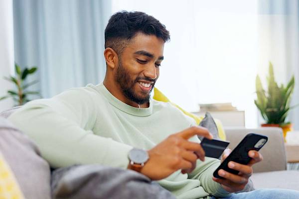 Young male smiling using mobile phone for banking