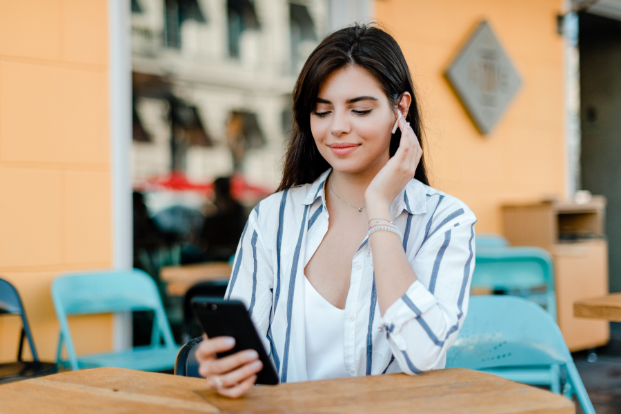 Young female looking at mobile phone wearing earpods